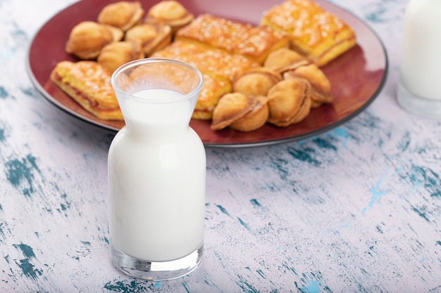 Pichet en verre de lait avec assiette de biscuits sucrés placés sur une table colorée.