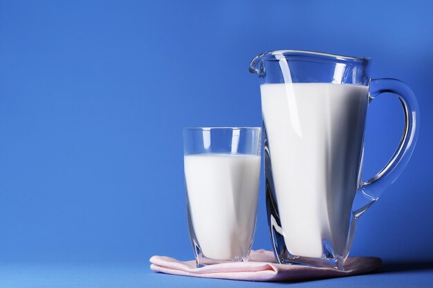 Pichet et verre de lait sur fond bleu