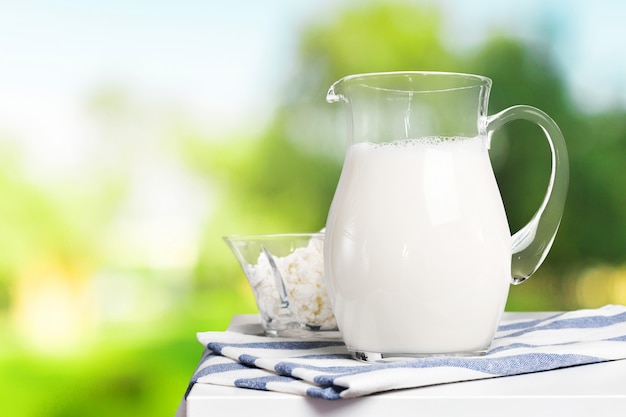 Pichet et un verre de lait sur une table en bois