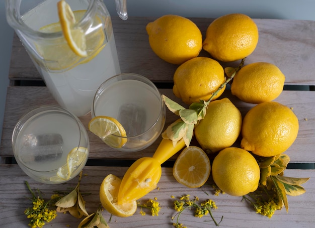 Photo pichet et verres de limonade citrons et fleurs jaunes vus d'en haut