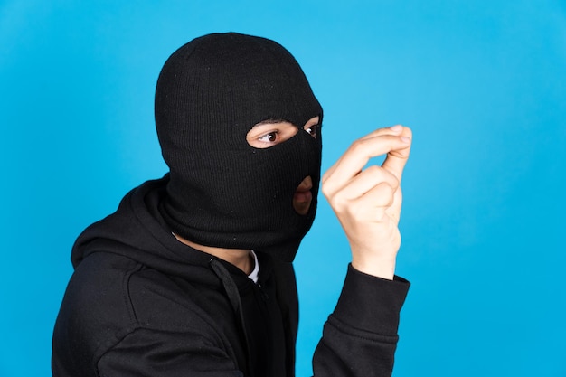 Pickpocket délinquant portant un masque de ski isolé sur fond bleu