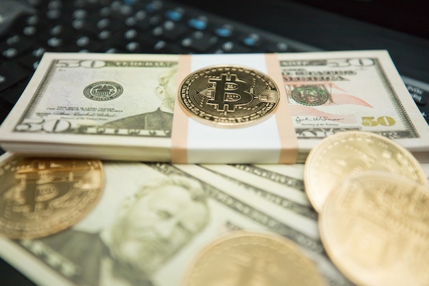Pièce de bitcoin d'or sur les dollars américains se bouchent. Image symbolique de la monnaie virtuelle.