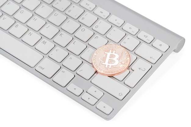 Pièce de cuivre bitcoin sur clavier blanc près de la touche Entrée isolée sur fond blanc