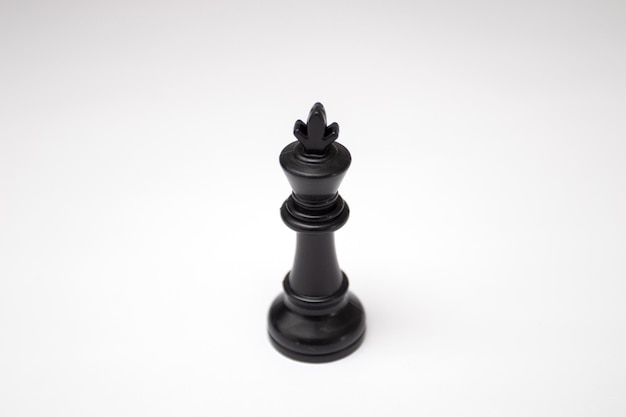 Pièce d'échecs du roi noir sur fond blanc.