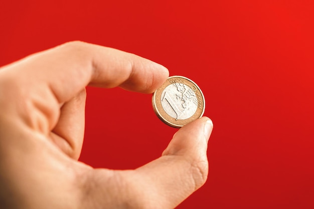 Pièce d'un euro dans la main de l'homme sur fond rouge