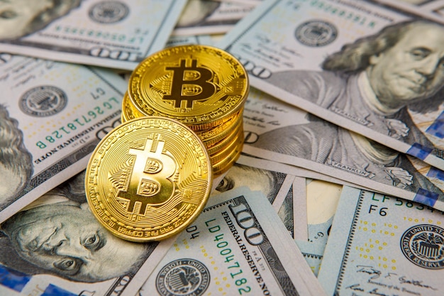 Pièce de monnaie bitcoin d'or sur des dollars américains en gros plan sur la monnaie crypto électronique