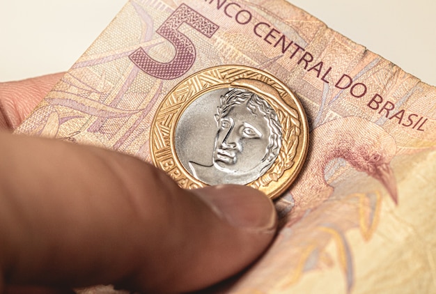 Photo une pièce de monnaie brésilienne sur un billet de banque brésilien de cinq reais en photo en gros