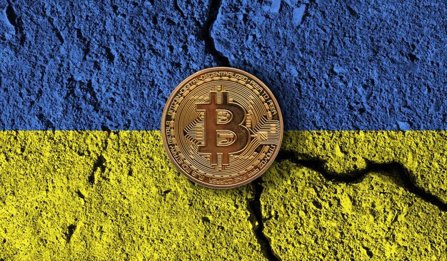 Pièce de monnaie crypto Bitcoin avec restrictions cryptographiques du drapeau ukrainien fissuré