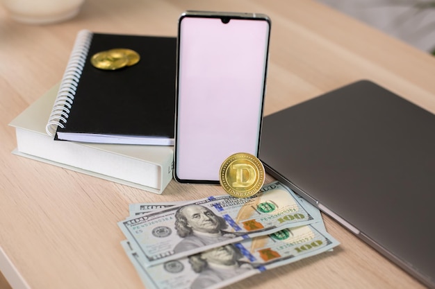 Pièce de monnaie crypto dorée et dollars américains avec écran vide de téléphone et ordinateur portable.