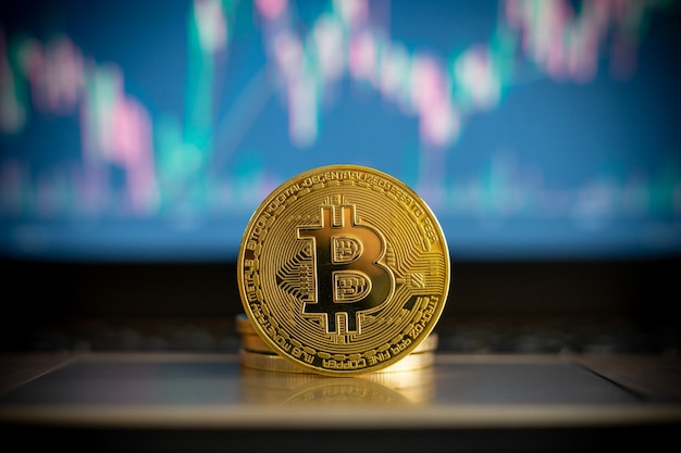 Pièce de monnaie de crypto-monnaie Bitcoin et tableau financier en arrière-plan
