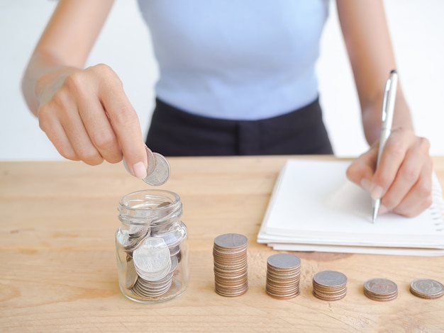 Pièce de monnaie en pot et pile de trésorerie sur bois avec image floue de slim et peau tan woman plan d'écriture pour économiser de l'argent