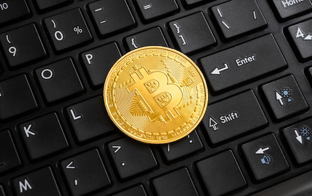 Pièce d'or Bitcoin sur clavier d'ordinateur noir.