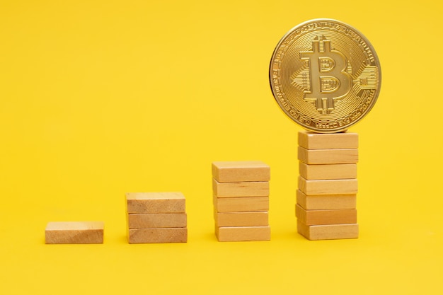 Pièce d'or Bitcoin sur une échelle de blocs de bois.