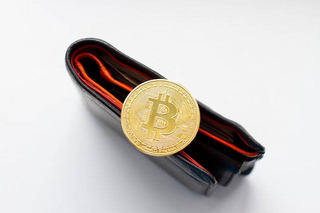 Pièce d'or Bitcoin sur portefeuille en cuir noir.