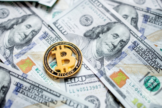 Une pièce symbolique de bitcoin sur les billets de cent dollars. Échangez de l'argent bitcoin pour un dollar.