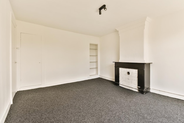 Photo une pièce vide avec des murs blancs et un tapis noir il y a un poêle à bois dans le mur à droite