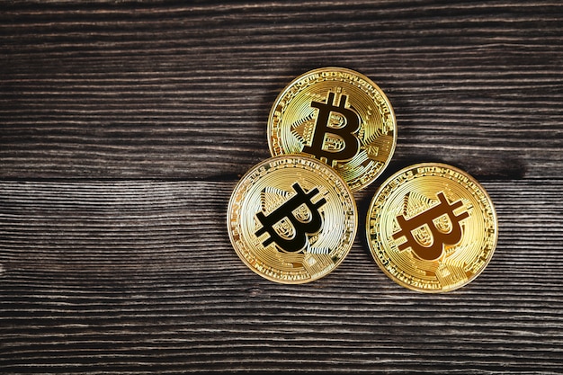 Pièces d'argent et d'or avec bitcoin, ondulation et symbole Ethereum sur bois.