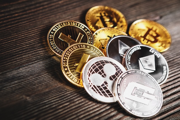 Pièces d'argent et d'or avec bitcoin, ondulation et symbole Ethereum sur bois.