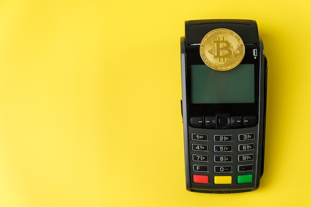 Pièces Bitcoin sur le terminal de paiement sur fond jaune