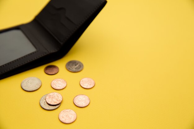 Pièces d'un dollar s'échappant d'un portefeuille en cuir gris ouvert.