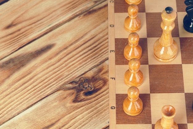 Photo pièces d'échecs sur un échiquier en bois sur un fond sombre