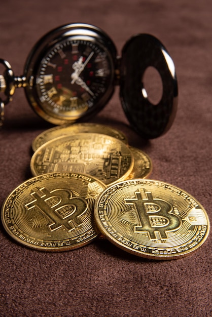 Pièces de monnaie bitcoin Bitcoin et une montre de poche vintage placées sur un fond en cuir marron mise au point sélective