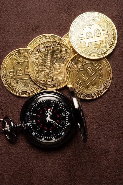 Pièces de monnaie Bitcoin bitcoin et une montre de poche vintage placées sur une vue de dessus de fond en cuir marron