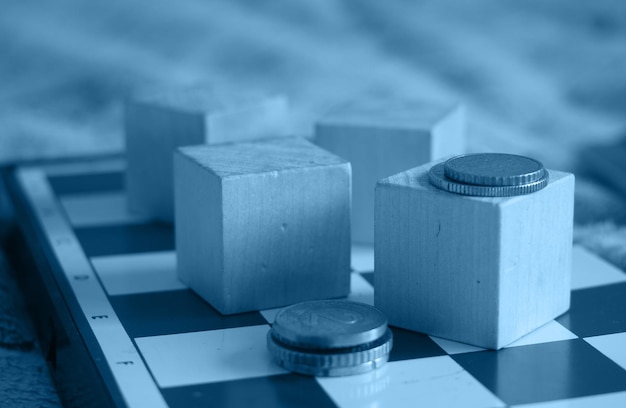 Pièces de monnaie sur l'échiquier et cubes en bois concept business background Image tonique au bleu classique