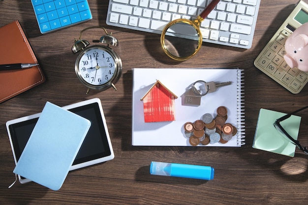 Pièces de monnaie, modèle de maison et clés avec des objets commerciaux.