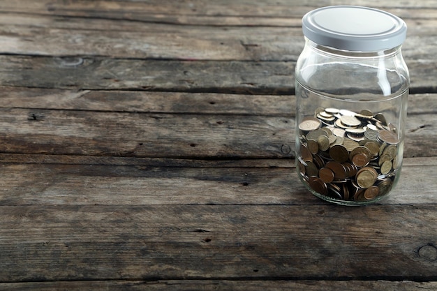 Pièces de monnaie en pot d'argent sur fond de bois