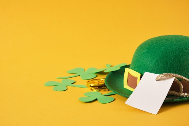 Pièces d'or chapeau de feutre de lutin vert décoratif et feuilles de trèfle foamiran sur fond jaune st patrick's day