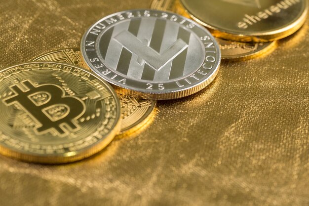 Pièces d'or de crypto-monnaie Bitcoin Ethereum Litecoin sur fond de pépites d'or Concept d'argent virtuel