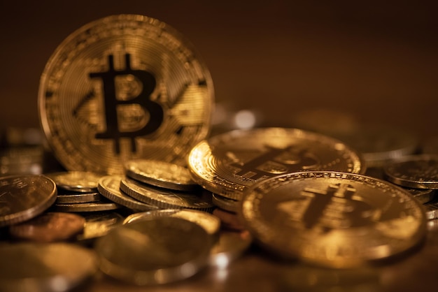 Pièces d'or éparpillées sur la surface avec un symbole bitcoin flou en arrière-plan