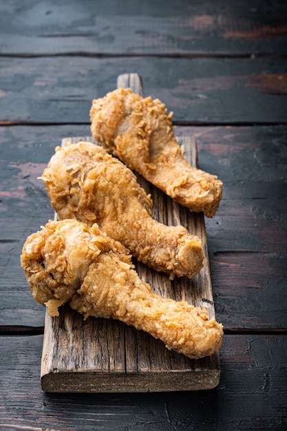 Pièces de pilon de poulet pané kentucky sur la vieille table en bois sombre