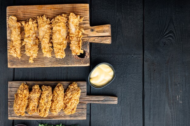 Pièces de poulet frit croustillant fait maison sur table en bois noir, mise à plat.