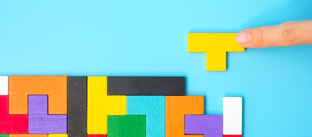 Pièces de puzzle en bois coloré sur fond bleu bloc de forme géométrique Concepts de pensée logique Solutions d'énigme stratégie rationnelle journée mondiale de la logique et éducation