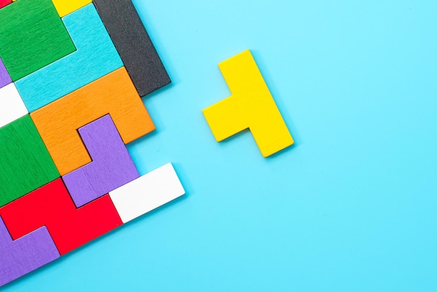 Pièces de puzzle en bois colorées sur fond bleu, bloc de forme géométrique. Concepts de pensée logique, énigme, solutions, rationnel, stratégie, journée mondiale de la logique et éducation