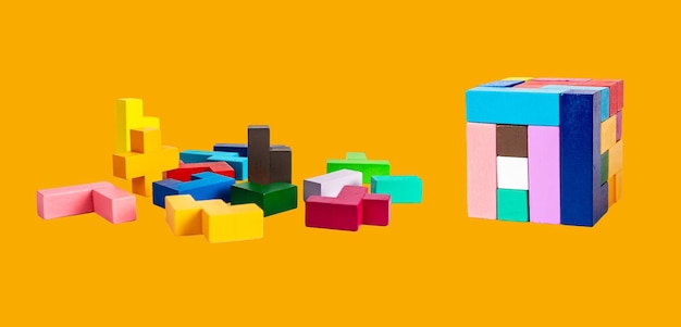 Pièces de puzzle en bois et cube sur fond orange Chaos et ordre ou concept de bâtiment de construction Jouet pour enfants