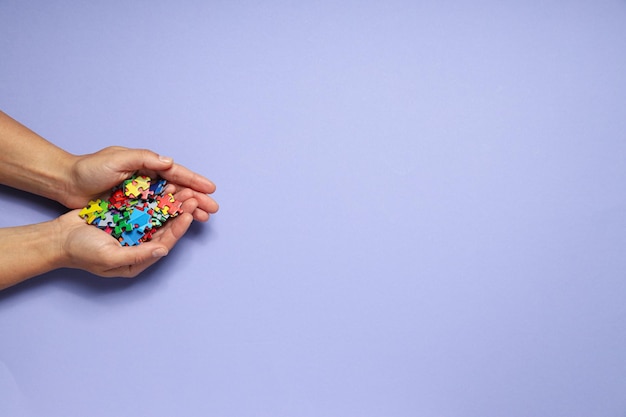 Pièces de puzzle multicolores dans les mains sur un fond clair place pour le texte Concept de la journée mondiale de l'autisme