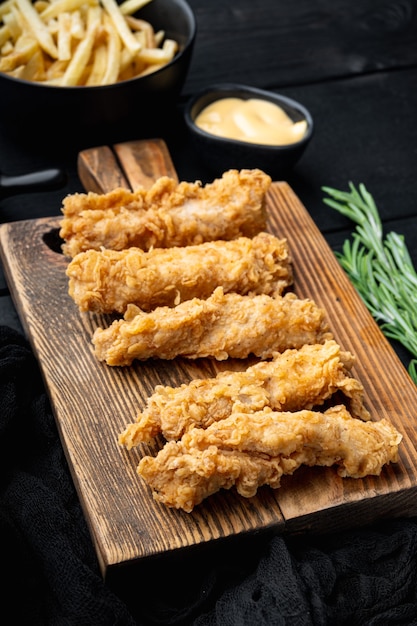 Pièces de rayures de poulet croustillant frit sur table en bois noir.