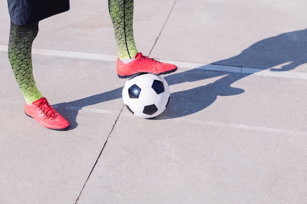 Pied sur un ballon de football sur un sol en béton