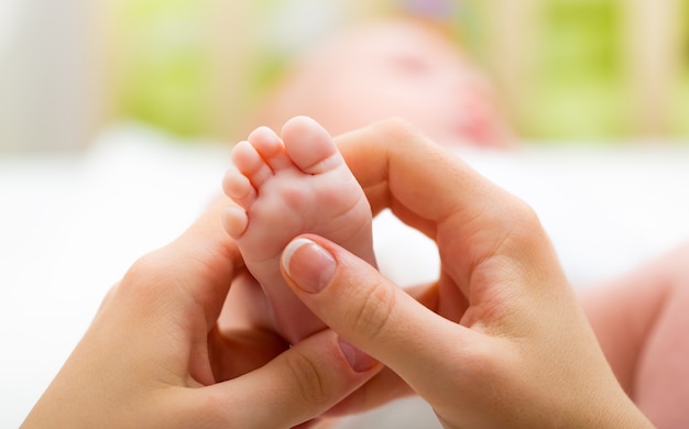 Pied de bébé dans les mains tendres de la mère, gros plan