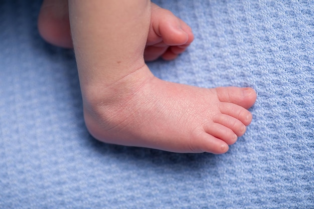 Le pied d'un bébé est allongé sur une couverture bleue.