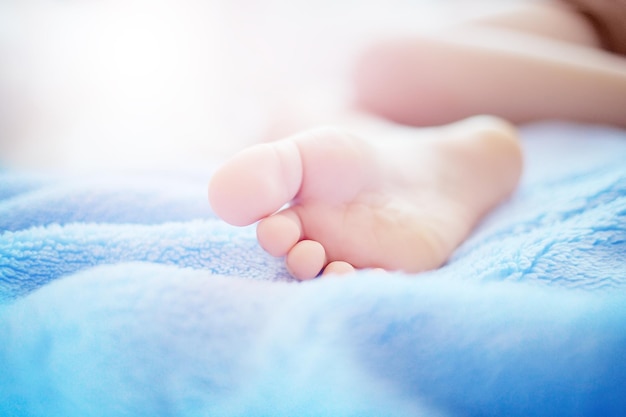 Un pied d'enfant sur une couverture bleue douce libre Le concept de tendresse sommeil sain ou soins du corps de bébé