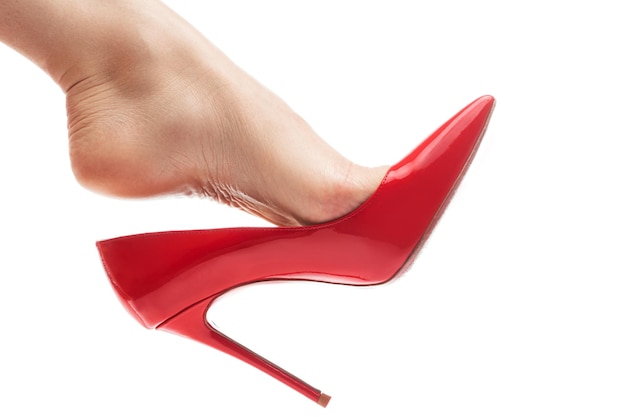 Pied féminin avec chaussures à talons aiguilles rouges sur fond blanc