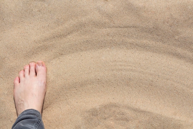 Le pied d'une femme sur le sable avec une copie de l'espace