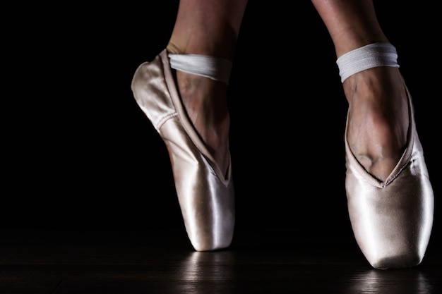 Pieds de ballerine classique en pointes sur le sol noir