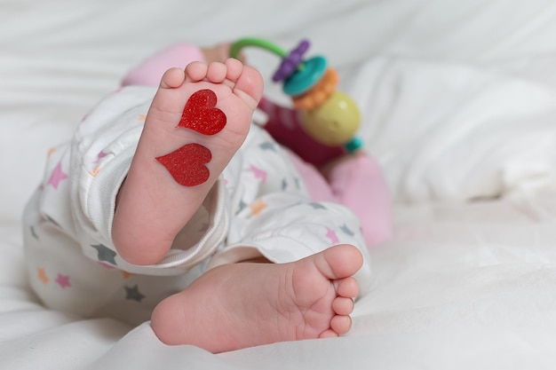 Pieds de bébé avec des coeurs sur leurs pieds Un nouveau-né est allongé sur le lit