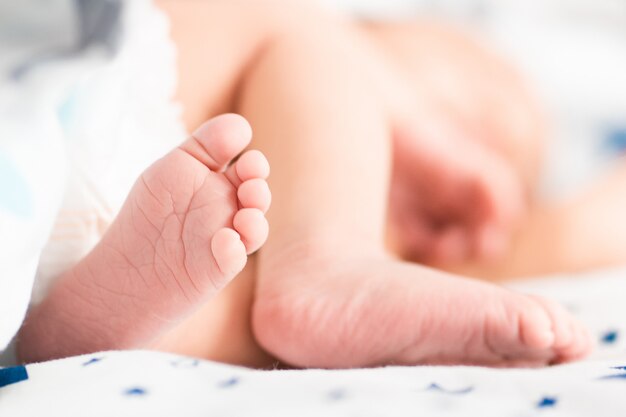 Pieds de bébé sur un couvre-lit blanc