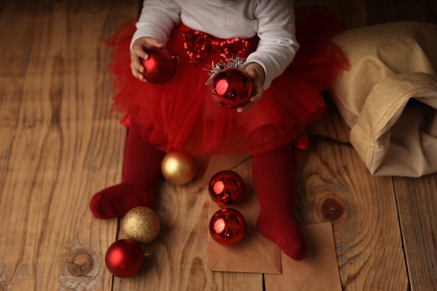 Pieds de bébé dans des chaussettes rouges autour des boules de Noël